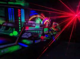 Laser tag arena glowing with red and blue lights as stags dart between cover points